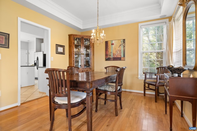 dining space with light wood-type flooring, a tray ceiling, crown molding, baseboards, and a chandelier