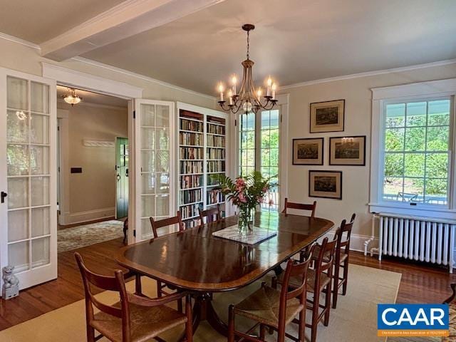 dining area featuring an inviting chandelier, radiator heating unit, a wealth of natural light, and wood finished floors