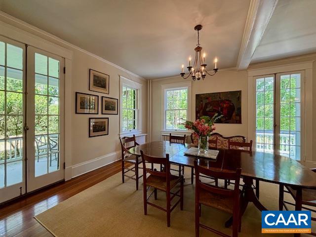 dining area with crown molding, an inviting chandelier, beam ceiling, baseboards, and wood finished floors