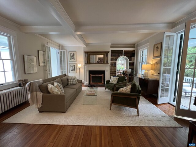 living room featuring radiator, a fireplace, hardwood / wood-style flooring, and beamed ceiling