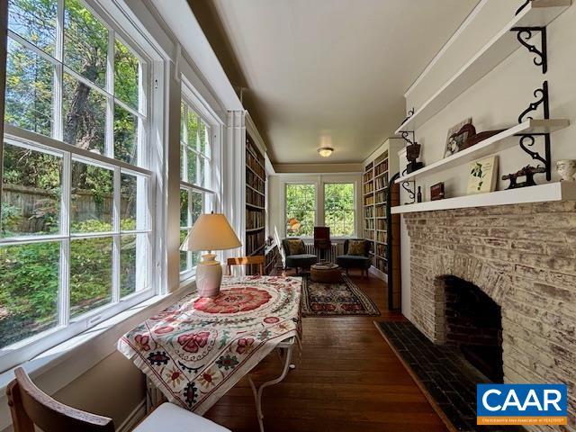 interior space with built in features, a brick fireplace, and wood finished floors