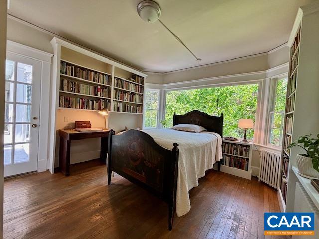 bedroom featuring ornamental molding, multiple windows, radiator heating unit, and hardwood / wood-style floors