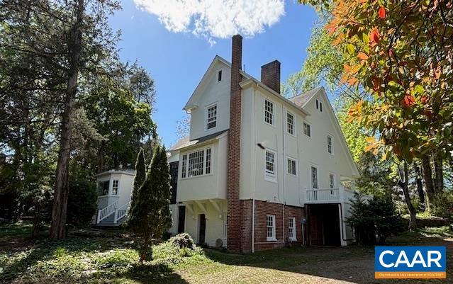 view of home's exterior with brick siding, stucco siding, and a chimney
