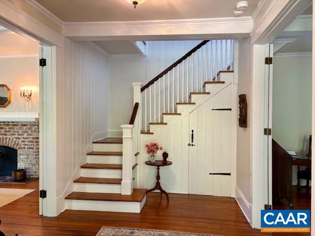 stairs featuring crown molding and wood finished floors
