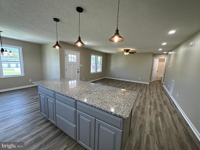 kitchen with dark hardwood / wood-style floors, hanging light fixtures, and light stone countertops