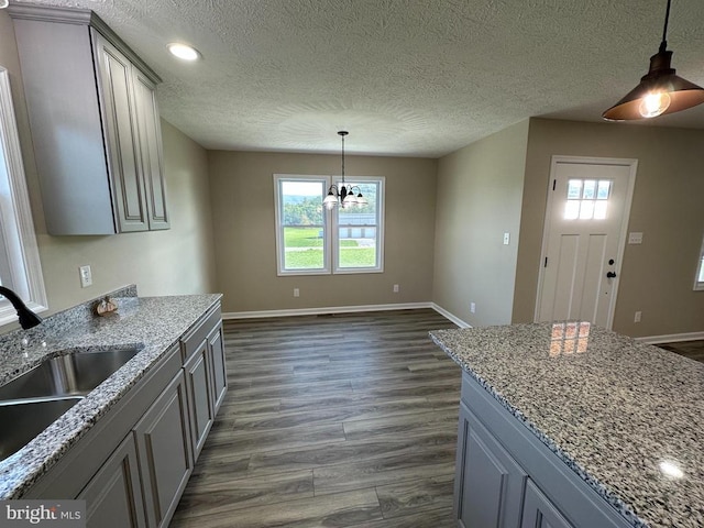 kitchen with dark wood-type flooring, light stone counters, and a healthy amount of sunlight