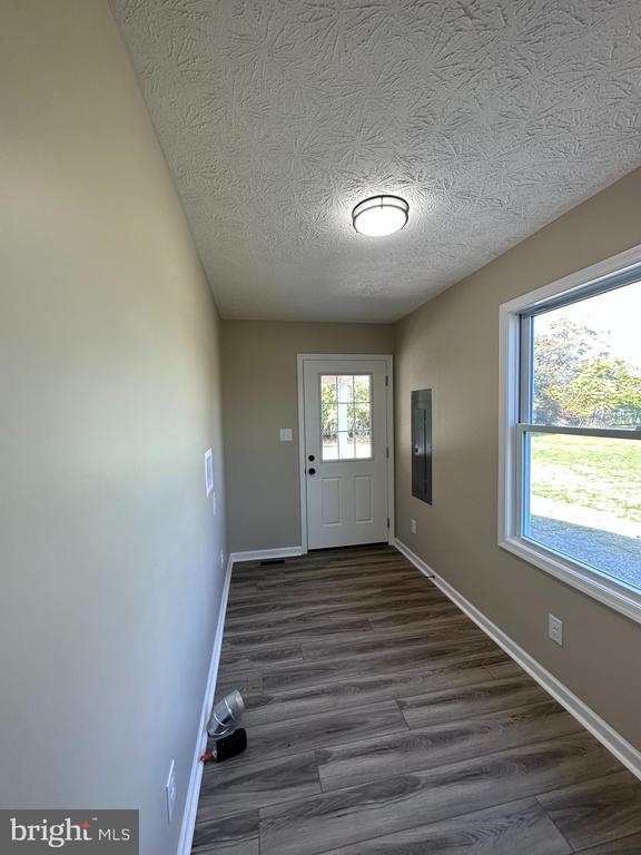 doorway to outside with dark hardwood / wood-style flooring and a textured ceiling