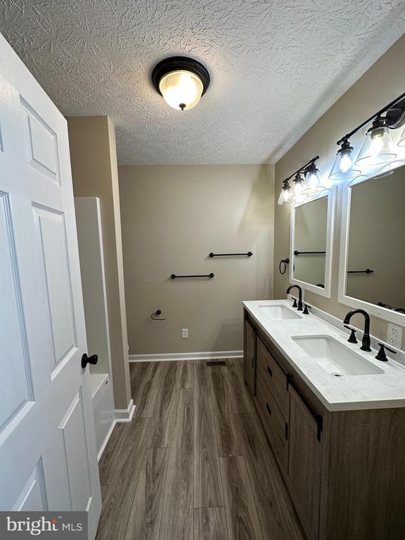 bathroom with double sink vanity, a textured ceiling, and hardwood / wood-style flooring