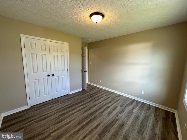 unfurnished bedroom featuring a textured ceiling, dark hardwood / wood-style floors, and a closet