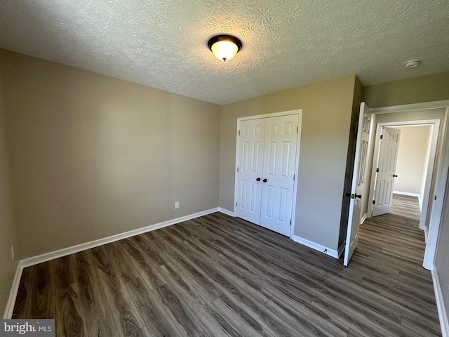 unfurnished bedroom with a closet, a textured ceiling, and dark hardwood / wood-style flooring