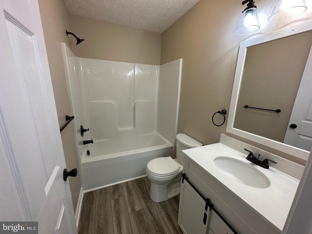 full bathroom featuring toilet, hardwood / wood-style flooring, a textured ceiling, vanity, and shower / bathtub combination