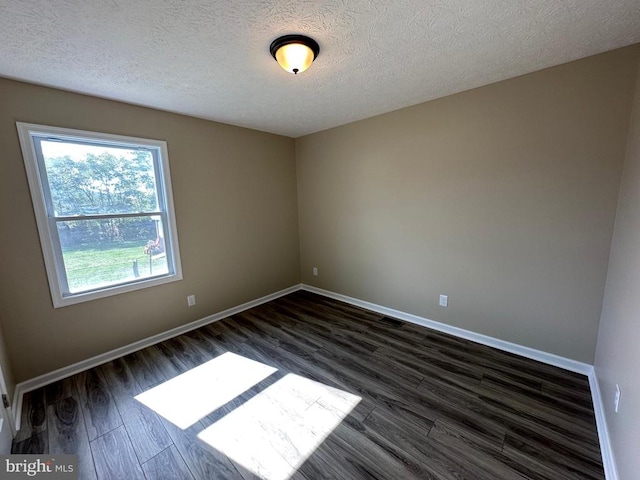 empty room with a textured ceiling and dark wood-type flooring