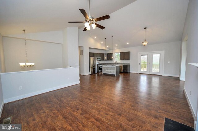 unfurnished living room featuring ceiling fan with notable chandelier, dark hardwood / wood-style flooring, and high vaulted ceiling