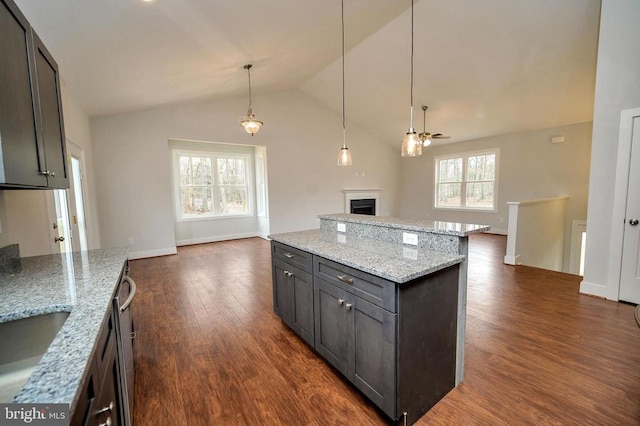 kitchen featuring ceiling fan, plenty of natural light, dark wood-type flooring, and light stone counters