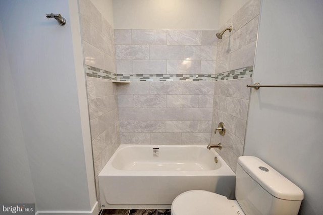 bathroom with wood-type flooring, tiled shower / bath, and toilet