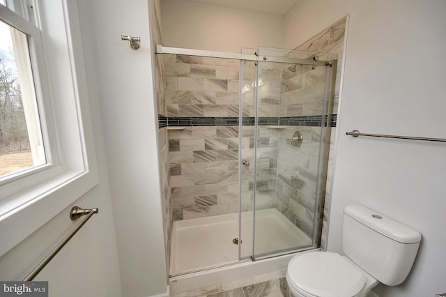 bathroom featuring a shower with door and toilet