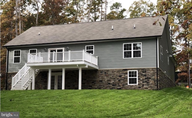 rear view of property featuring french doors, a lawn, and a deck