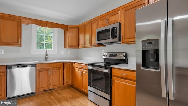 kitchen featuring stainless steel appliances, light hardwood / wood-style floors, and sink