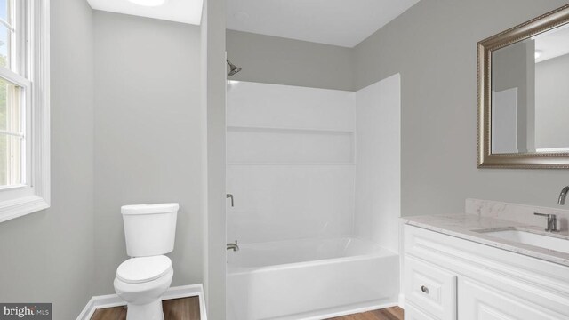 full bathroom with shower / washtub combination, vanity with extensive cabinet space, hardwood / wood-style floors, and toilet