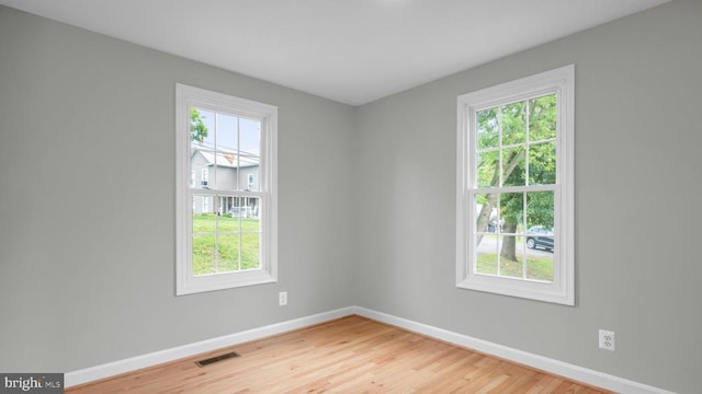 unfurnished room featuring a healthy amount of sunlight and hardwood / wood-style floors