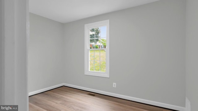 spare room with a healthy amount of sunlight and hardwood / wood-style floors