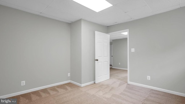 spare room with light colored carpet and a paneled ceiling