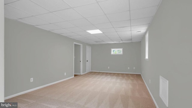 carpeted spare room featuring a drop ceiling