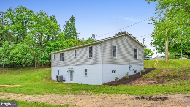 view of property exterior with central AC and a lawn