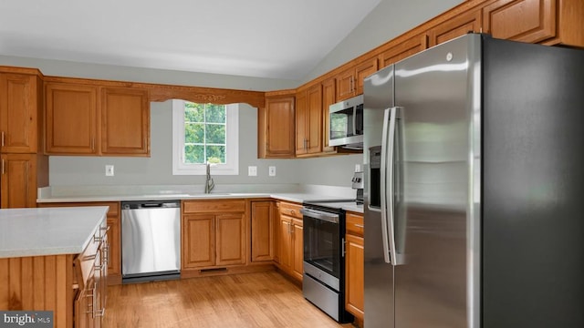 kitchen with lofted ceiling, light wood-type flooring, sink, and appliances with stainless steel finishes