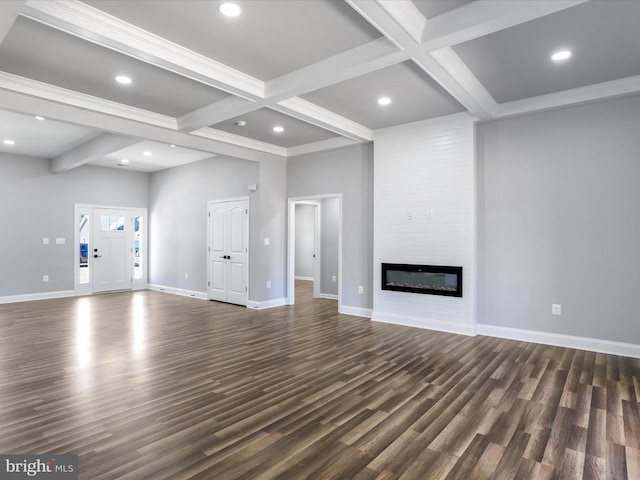 unfurnished living room featuring beam ceiling, a large fireplace, coffered ceiling, dark hardwood / wood-style floors, and a towering ceiling