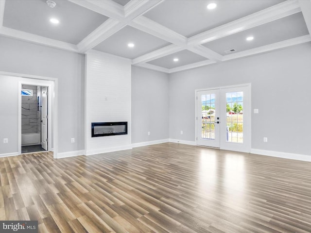 unfurnished living room featuring beam ceiling, a large fireplace, french doors, coffered ceiling, and light hardwood / wood-style flooring