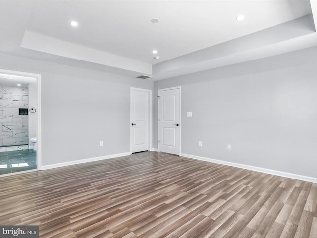 empty room featuring light hardwood / wood-style floors and a raised ceiling