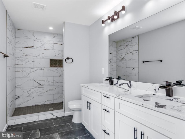 bathroom with vanity, toilet, and tiled shower