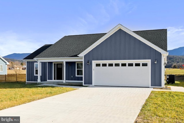 view of front of house with central AC unit, a mountain view, a garage, and a front lawn