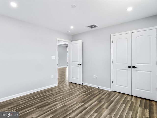 unfurnished bedroom with a closet and dark wood-type flooring