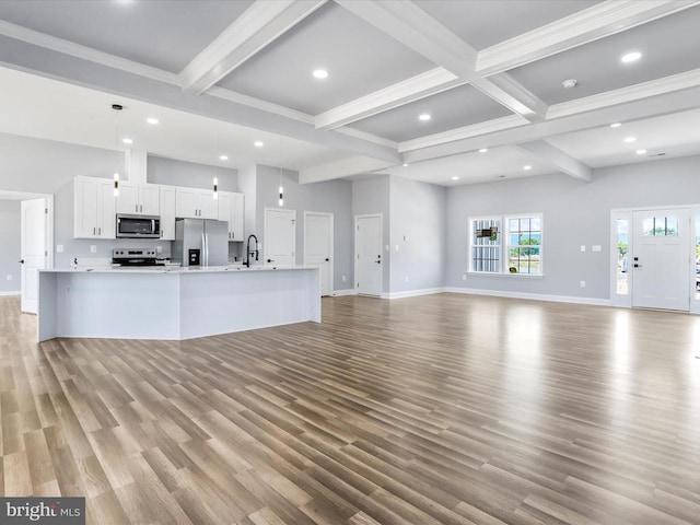 unfurnished living room featuring beamed ceiling, light hardwood / wood-style floors, sink, and coffered ceiling