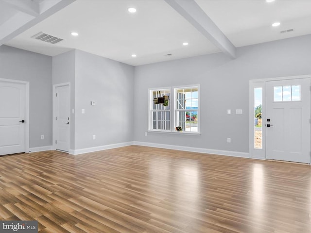 foyer entrance featuring beam ceiling, light wood-type flooring, and a healthy amount of sunlight