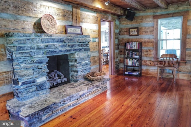 living room with beam ceiling, dark hardwood / wood-style flooring, wooden ceiling, and a stone fireplace