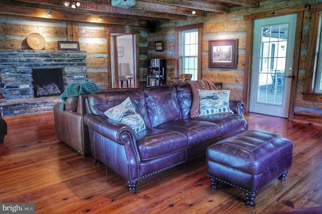 living room with beamed ceiling, hardwood / wood-style floors, a fireplace, and wooden walls