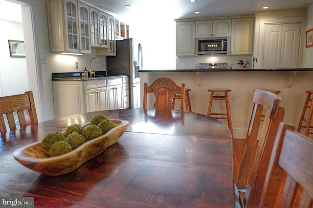 kitchen featuring a kitchen bar, cream cabinetry, stainless steel appliances, and sink