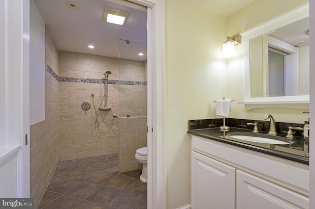 bathroom featuring a tile shower, vanity, and toilet