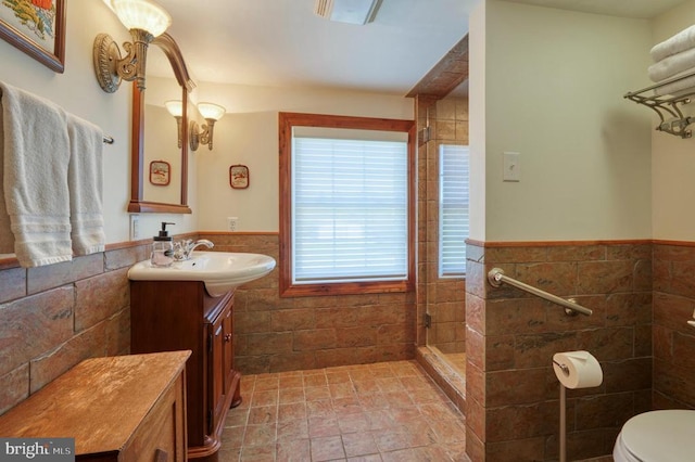 bathroom featuring vanity, toilet, tile walls, and a tile shower