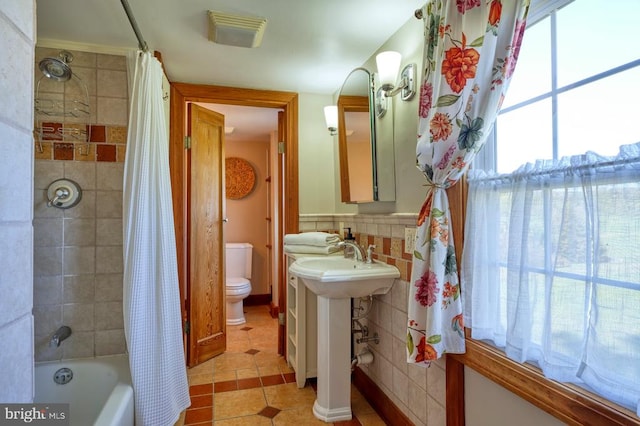 full bathroom with sink, tile patterned flooring, toilet, shower / bath combo with shower curtain, and tile walls