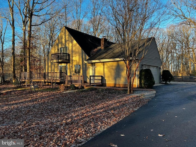 view of home's exterior with a balcony, a garage, and a wooden deck