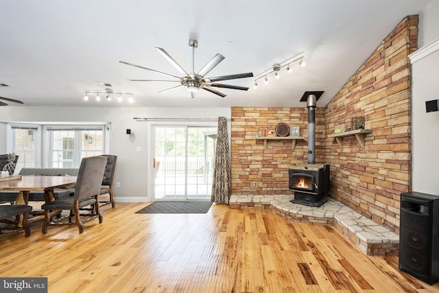 living room with a wood stove, ceiling fan, light hardwood / wood-style floors, and lofted ceiling