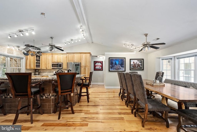 dining area featuring ceiling fan, vaulted ceiling, and light hardwood / wood-style flooring