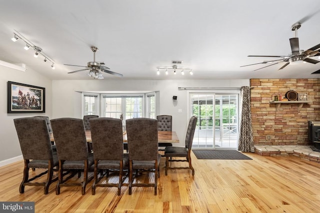 dining space featuring ceiling fan, light wood-type flooring, and a wood stove