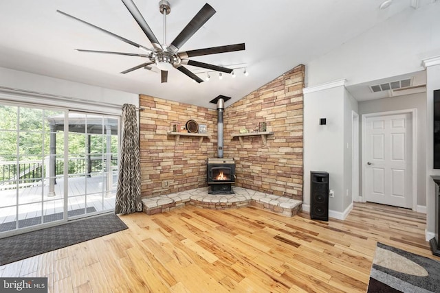 unfurnished living room featuring lofted ceiling, ceiling fan, wood-type flooring, and a wood stove