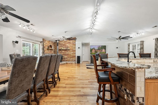 dining room with a wood stove, light hardwood / wood-style floors, and vaulted ceiling