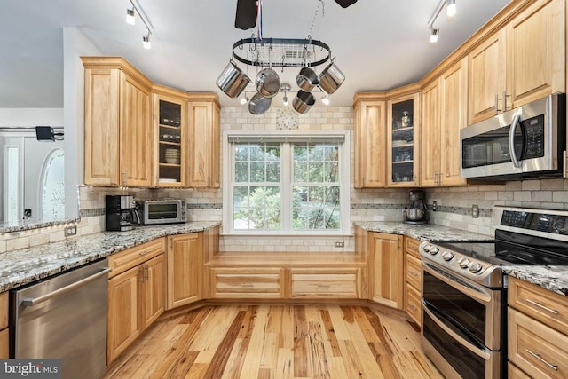 kitchen featuring light hardwood / wood-style flooring, light brown cabinetry, tasteful backsplash, appliances with stainless steel finishes, and light stone counters